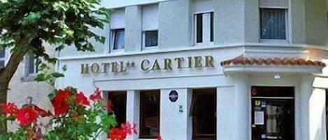 Un hotel llamado "HOTEL CARTIER" de estilo arquitectónico clásico, con una entrada destacada y un balcón.