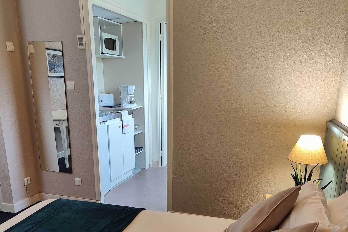 Une chambre d’hôtel avec un lit, une lampe de chevet et une vue sur la cuisine.