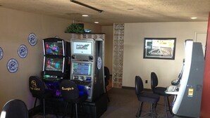 Une salle avec des jeux d’arcade, un bar et un tableau encadré au mur.