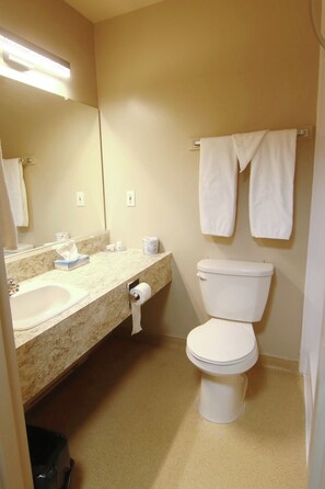 A bathroom with a sink, toilet, and two towels hanging on a rack. - Keystone Motor Inn, a Travelodge by Wyndham (Brandon)