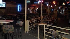 L’intérieur d’un restaurant à la lumière tamisée, avec des tables, des chaises, un comptoir et un écran de télévision.
