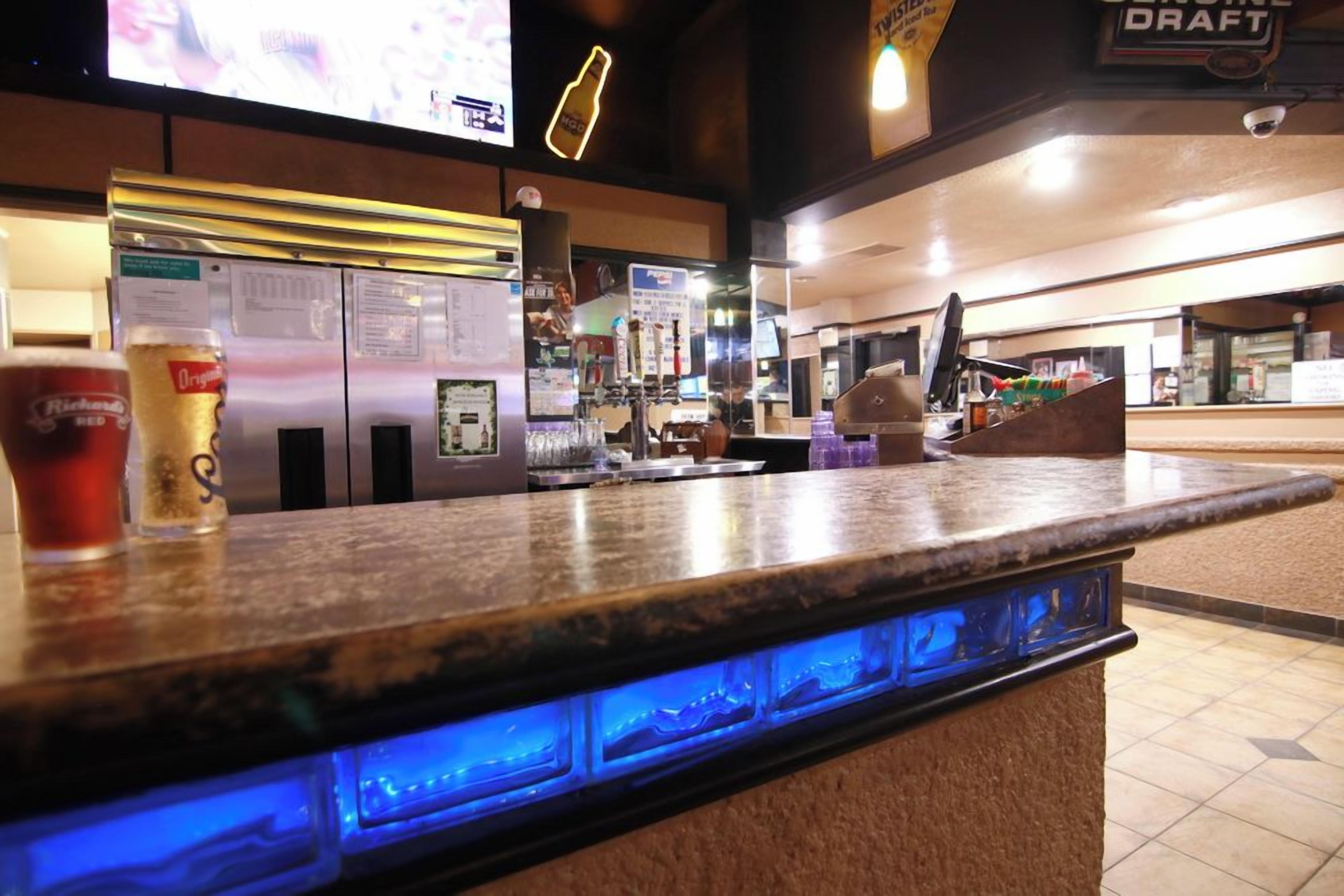 A bar area with a counter, a refrigerator, and a beer tap.