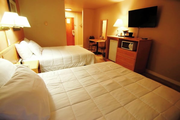 Habitación de hotel con dos camas, un escritorio, televisor y microondas.