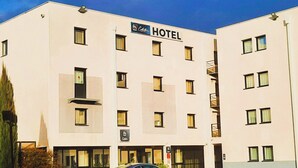 A modern hotel building with a sign indicating it is a hotel. There are multiple windows and a parking sign visible.