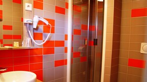 A bathroom with a glass-enclosed shower, a white sink, and a mirror.