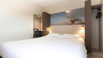Habitación de hotel con una cama grande, un escritorio y un cuadro colgado en la pared.