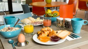 A breakfast setting with a bowl of cereal, croissants, toast, and juice.