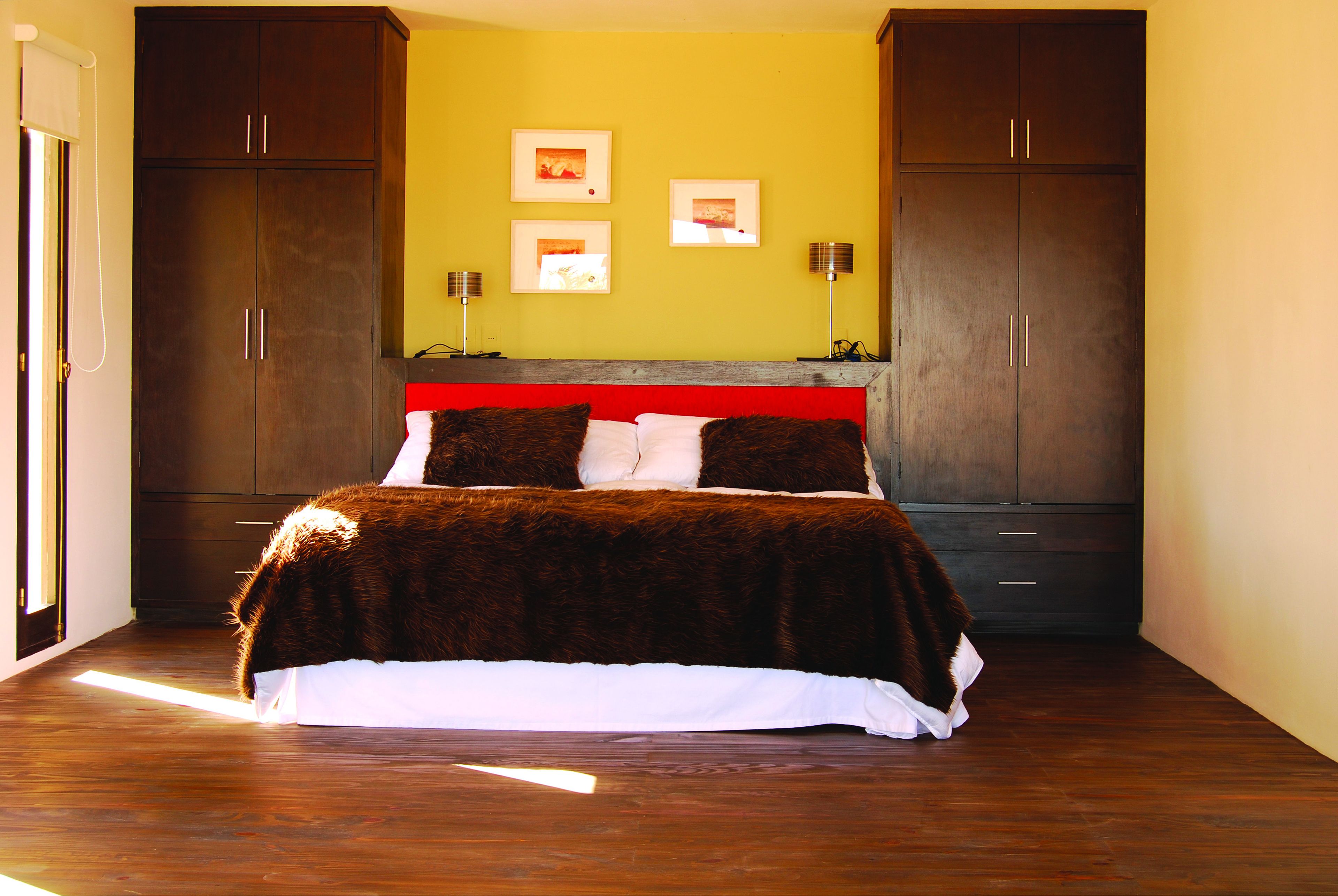 Un dormitorio con una cama grande, dos mesitas de noche, un armario y un cabecero.