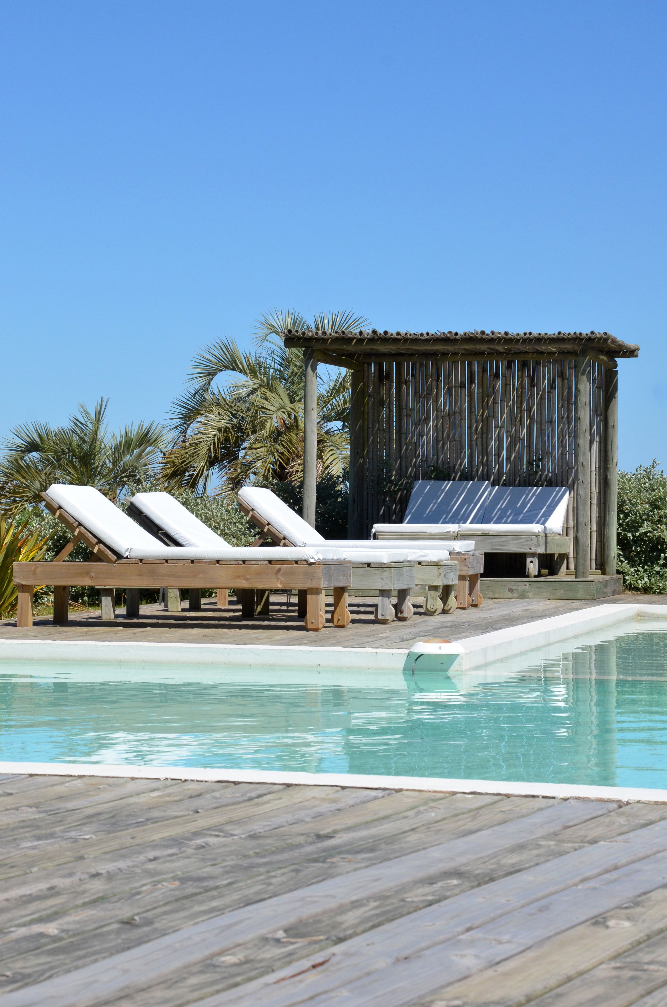 A wooden deck with three sun loungers and a small wooden structure with a solar panel.