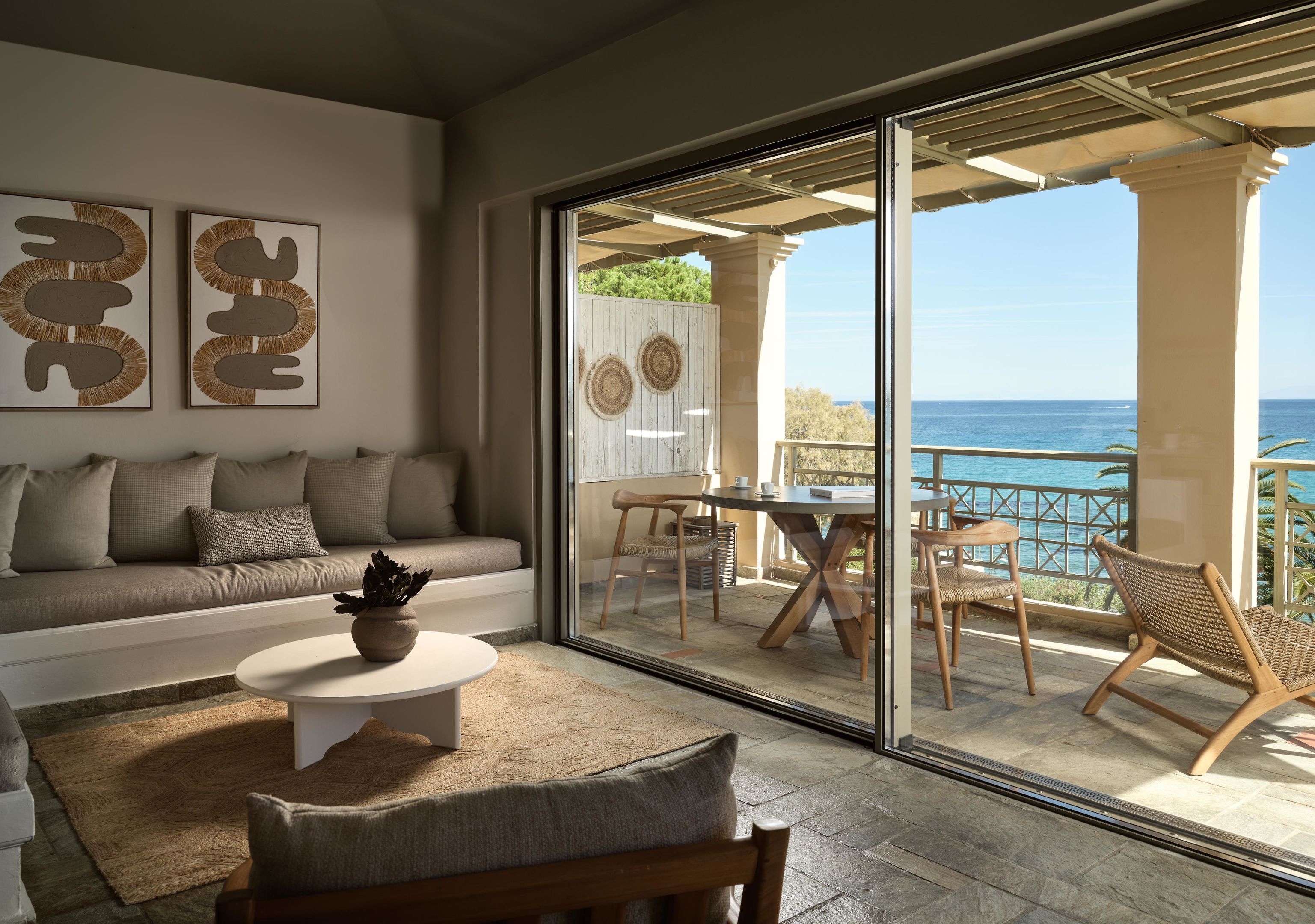 A modern living room with a sofa, coffee table, and a view of the ocean through large sliding glass doors.