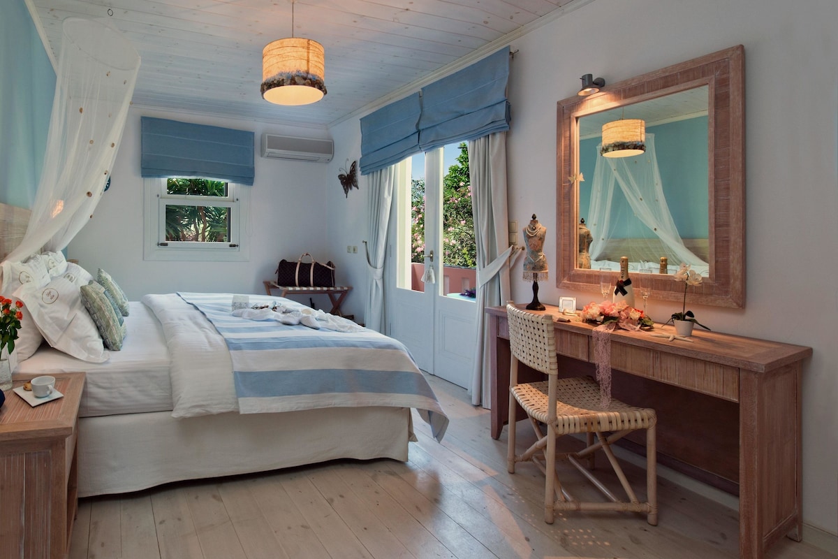 A bedroom with a bed, bedside table, chair, desk, and a large mirror.