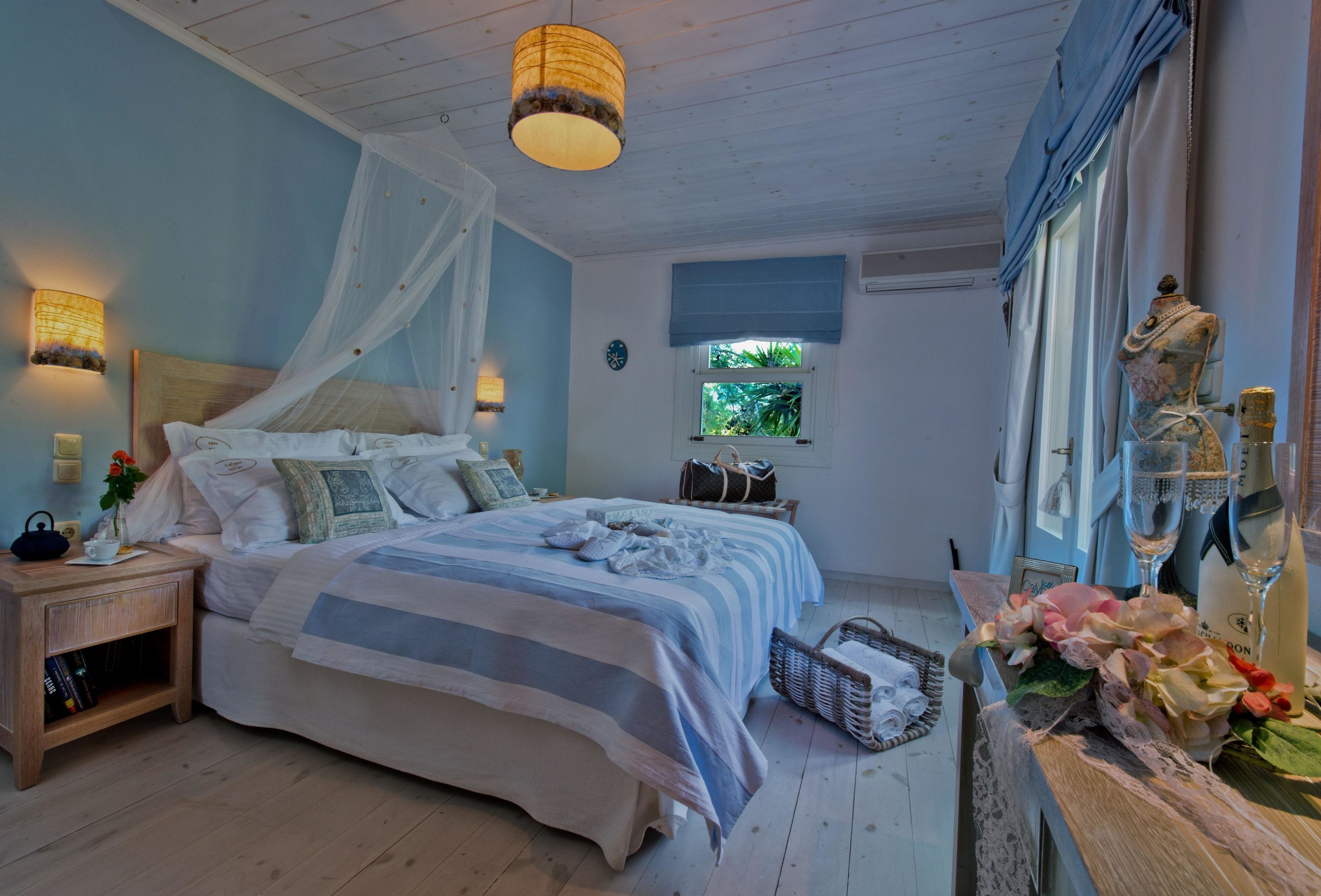 A bedroom with a bed, bedside table, lamp, window, and decorative items.