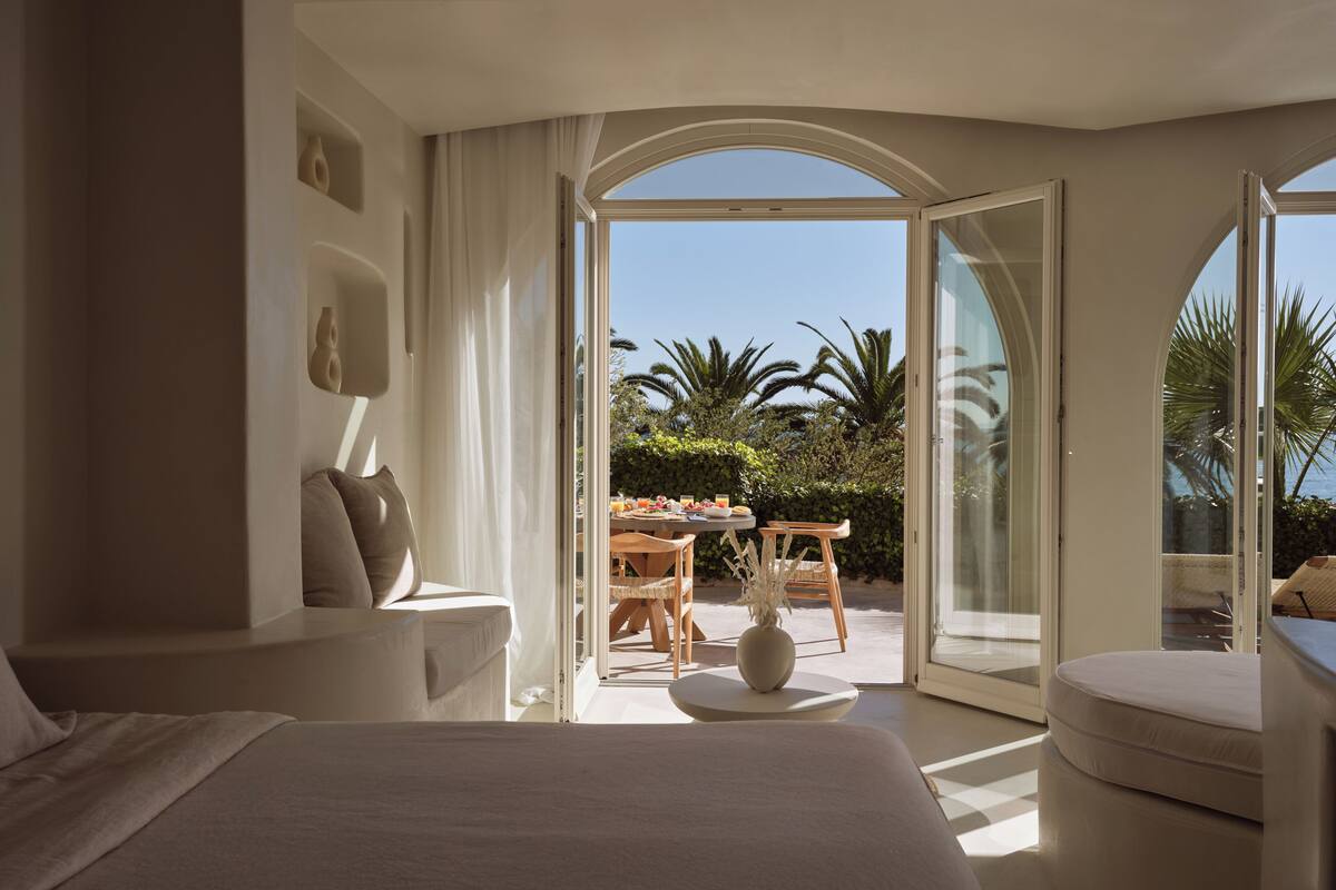 Un dormitorio con una cama grande, un sofá y una zona de comedor con mesa y sillas.