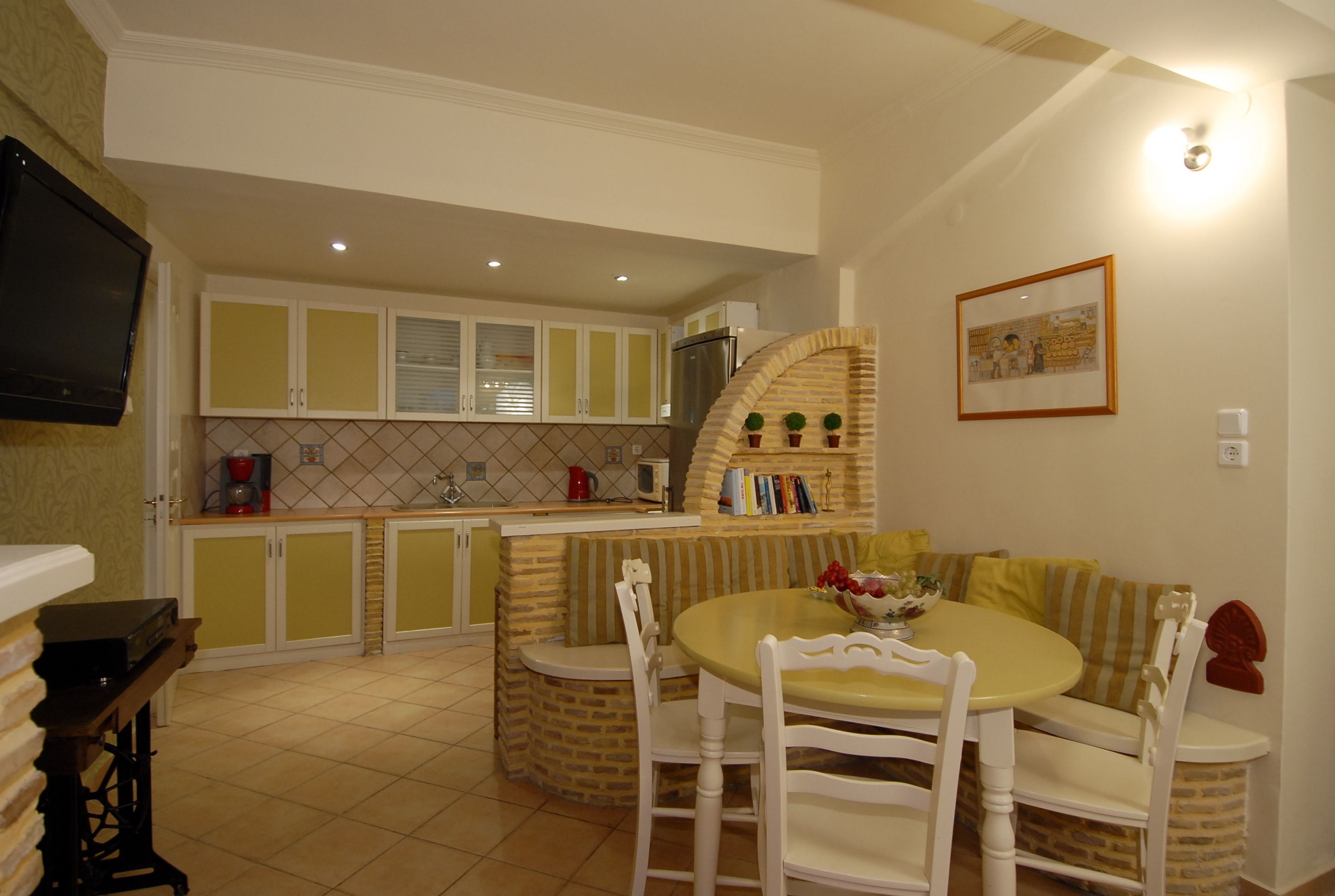 A kitchen with a dining area, featuring a round table, white chairs, and a built-in bench.