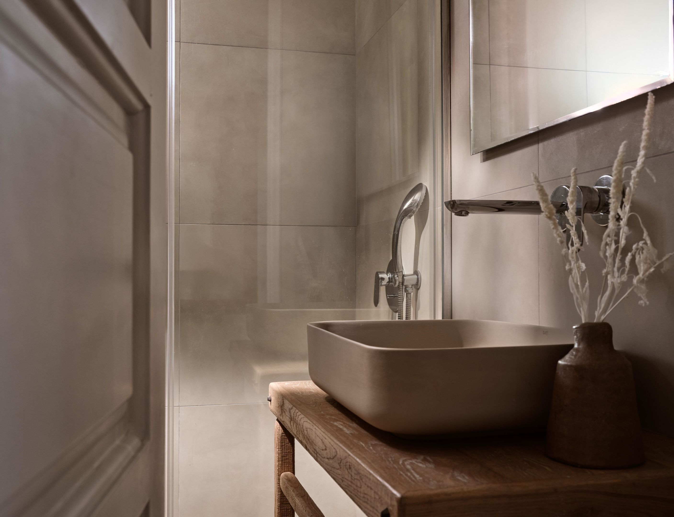 A bathroom with a modern sink, a mirror, and a shower.