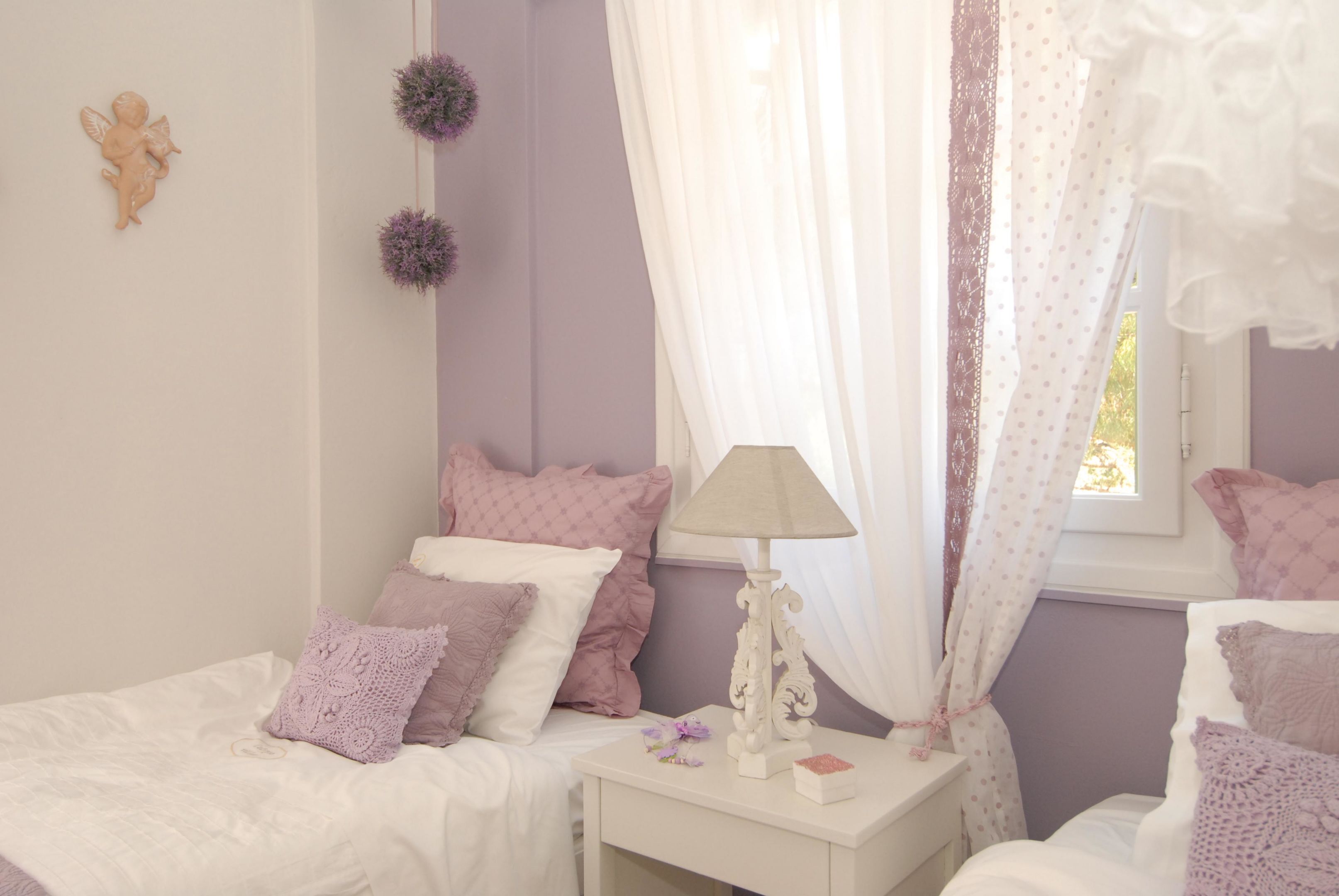 A bedroom with two beds, a nightstand with a lamp, and decorative items.