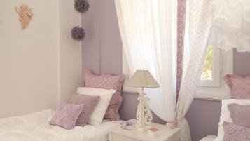 A bedroom with two beds, a nightstand with a lamp, and decorative items.