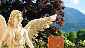 A statue of an angel with wings, placed on a pedestal with a sign reading "Ausgezeichnete Feriensitzung." - Enzianbrenner Bed & Breakfast (Hermagor-Pressegger See)