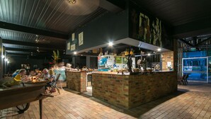 An indoor dining area with brick flooring, a central island with a counter, and a mural on the wall. - Daintree Wild Zoo & B&B (Lower Daintree)