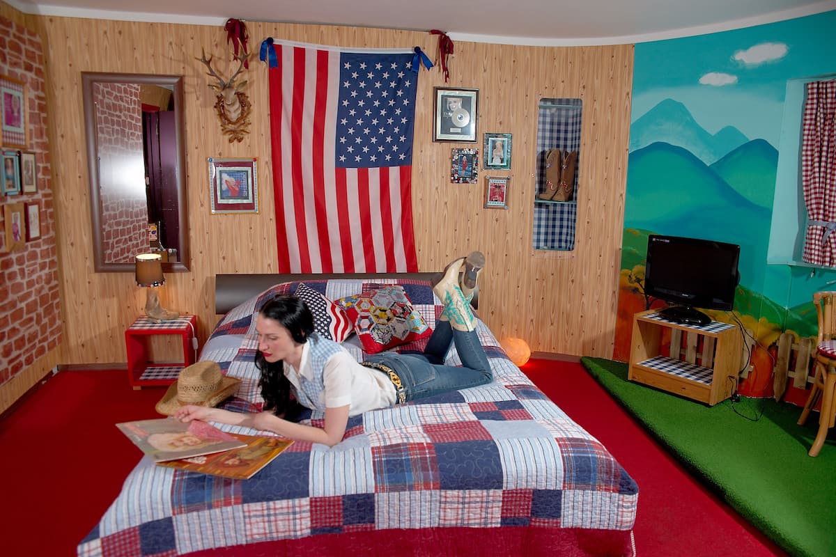 Ein Zimmer mit einem großen Bett, einem Fernseher und einem Wandgemälde.