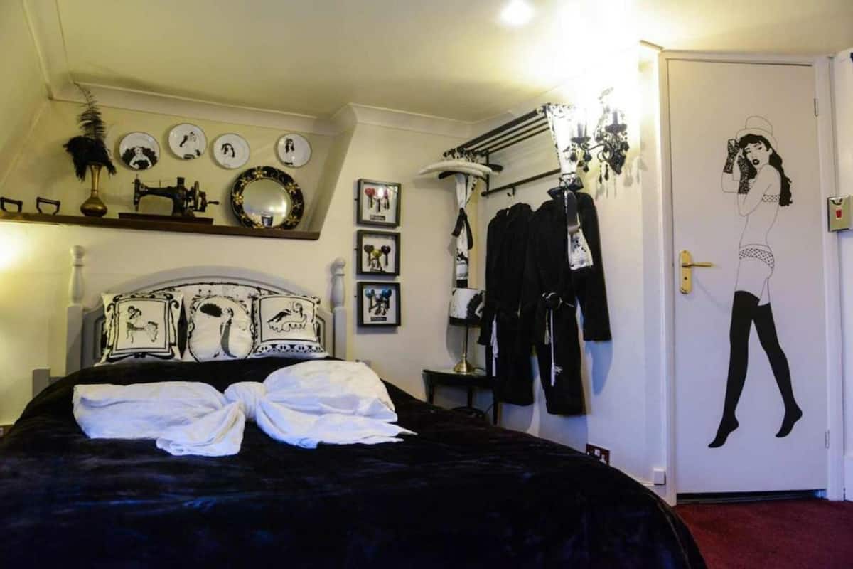 Ein Schlafzimmer mit einem Bett, einem Schminktisch, einem Spiegel und einer Tür mit schwarzer Silhouette-Dekoration.
