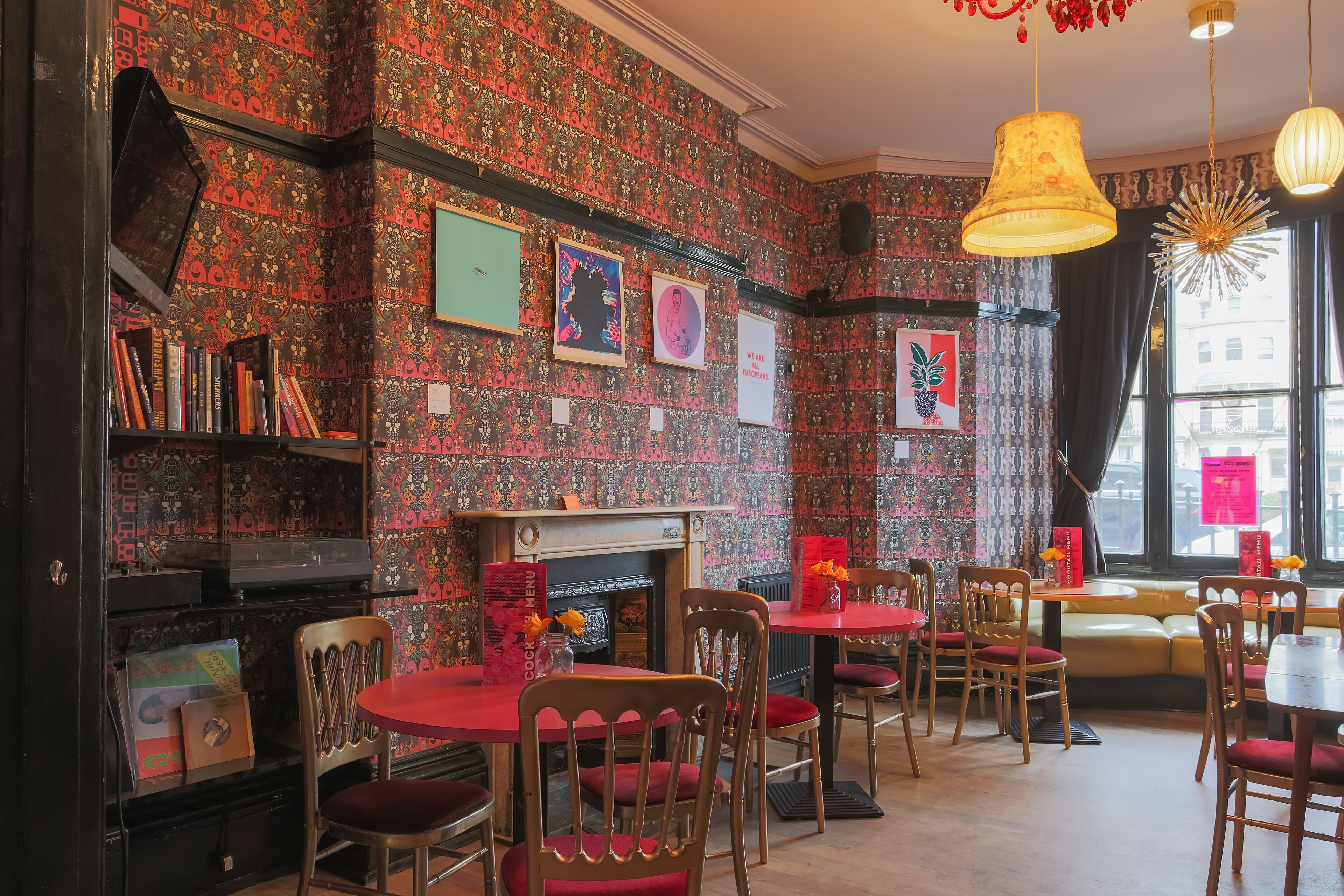 Un restaurant chaleureux avec un papier peint à motifs, une cheminée et des meubles en bois.