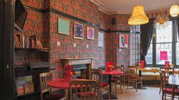 Un restaurant chaleureux avec un papier peint à motifs, une cheminée et des meubles en bois.