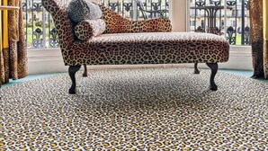 A room with a leopard print sofa, large windows, and a patterned rug.
