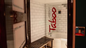 A bathroom with a white tiled wall, a wooden bench, and a bathtub.