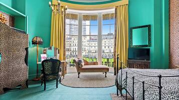 Una habitación con un ventanal grande, un sofá, un televisor y detalles decorativos con estampado de leopardo.