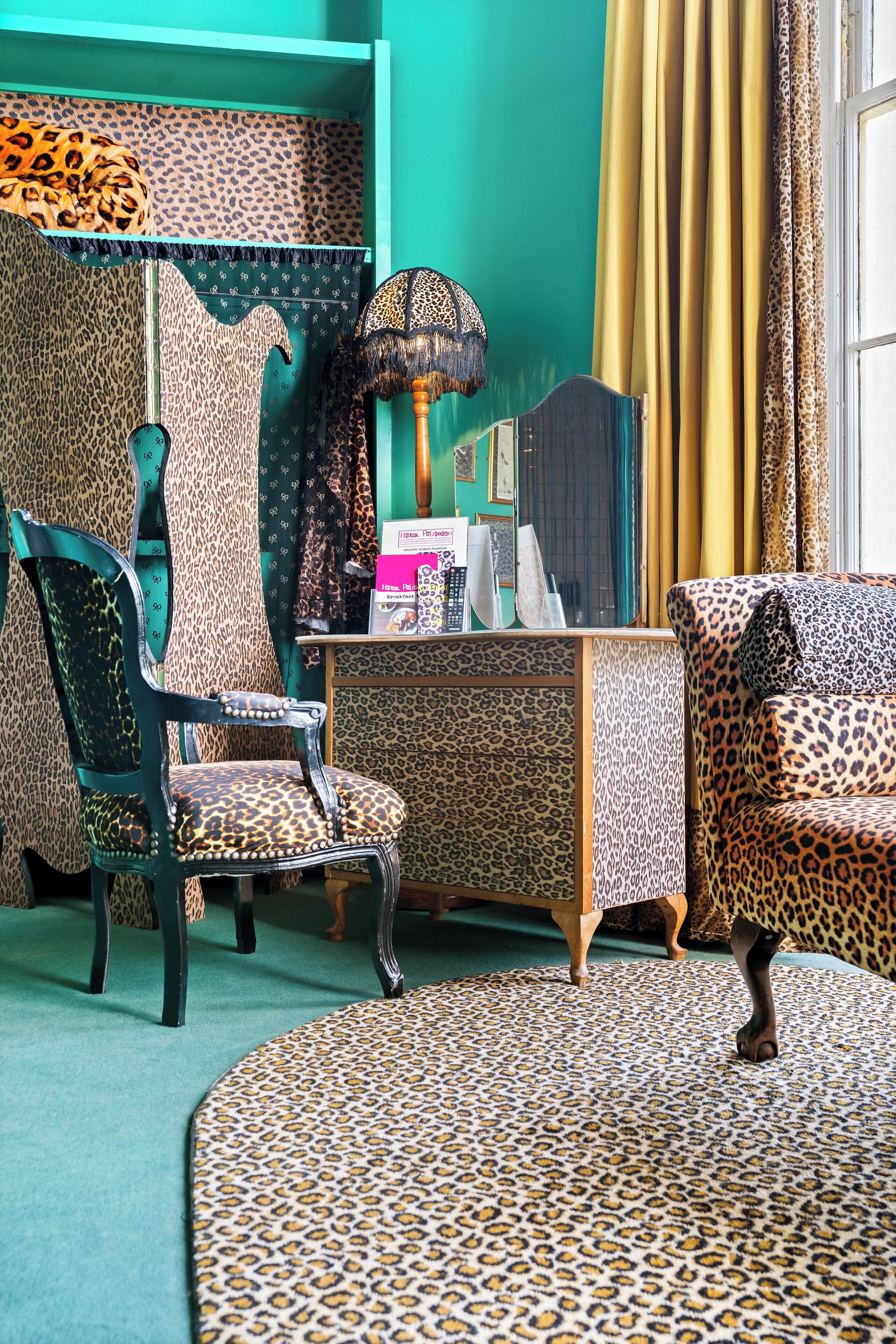 A room with leopard print upholstery, a vintage lamp, and a green carpet.