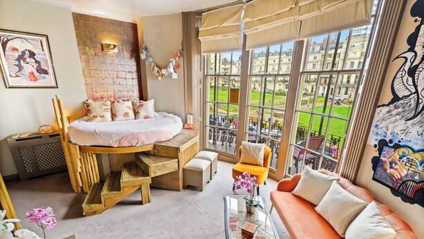 A bedroom with a bed, a sofa, a coffee table, and a view of a courtyard.