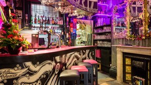 A bar area with a counter, stools, and shelves stocked with bottles.
