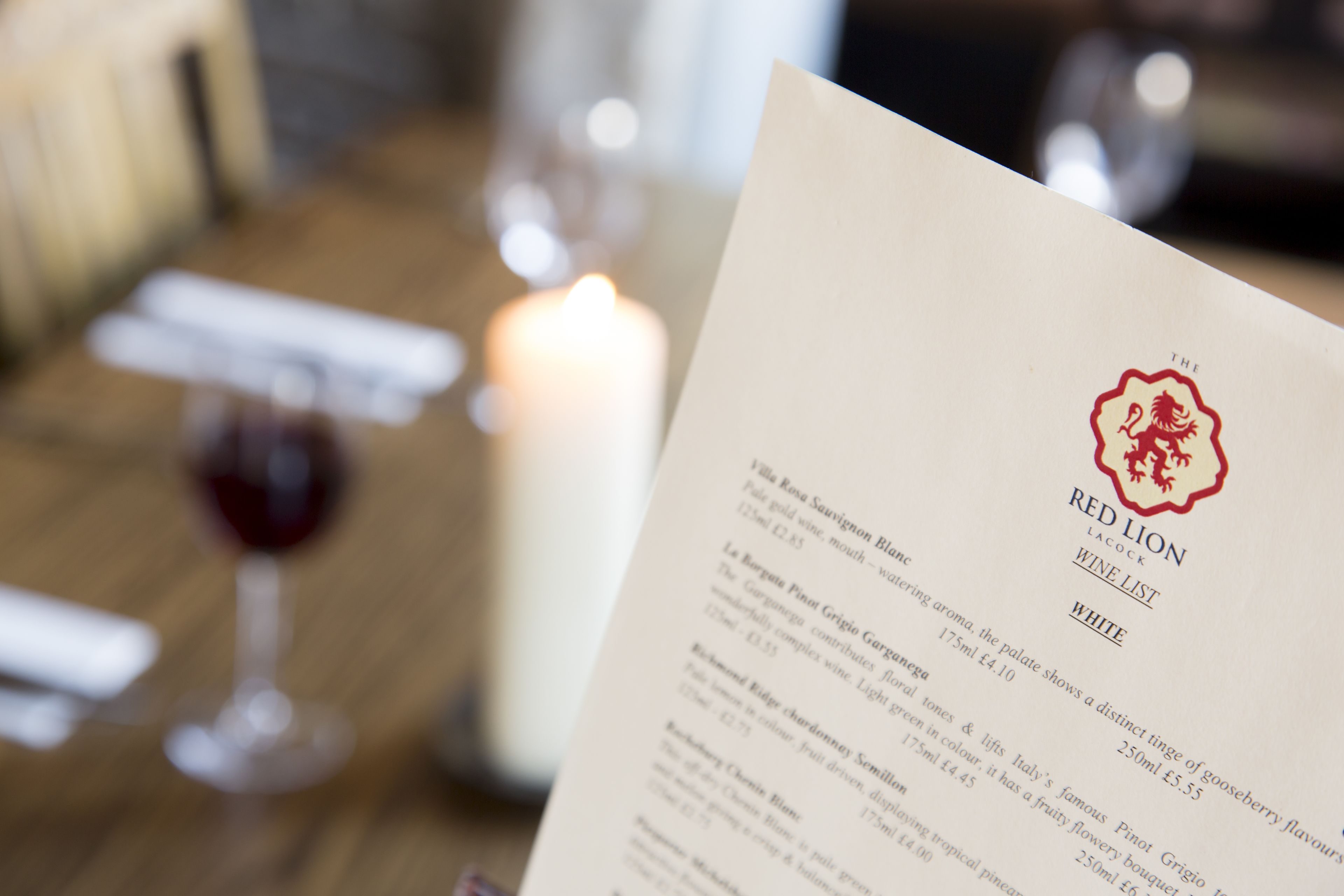 Un menú con la carta de vinos Red Lion, que presenta diversas opciones de vinos y sus precios.