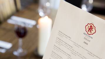 Un menú con la carta de vinos Red Lion, que presenta diversas opciones de vinos y sus precios.