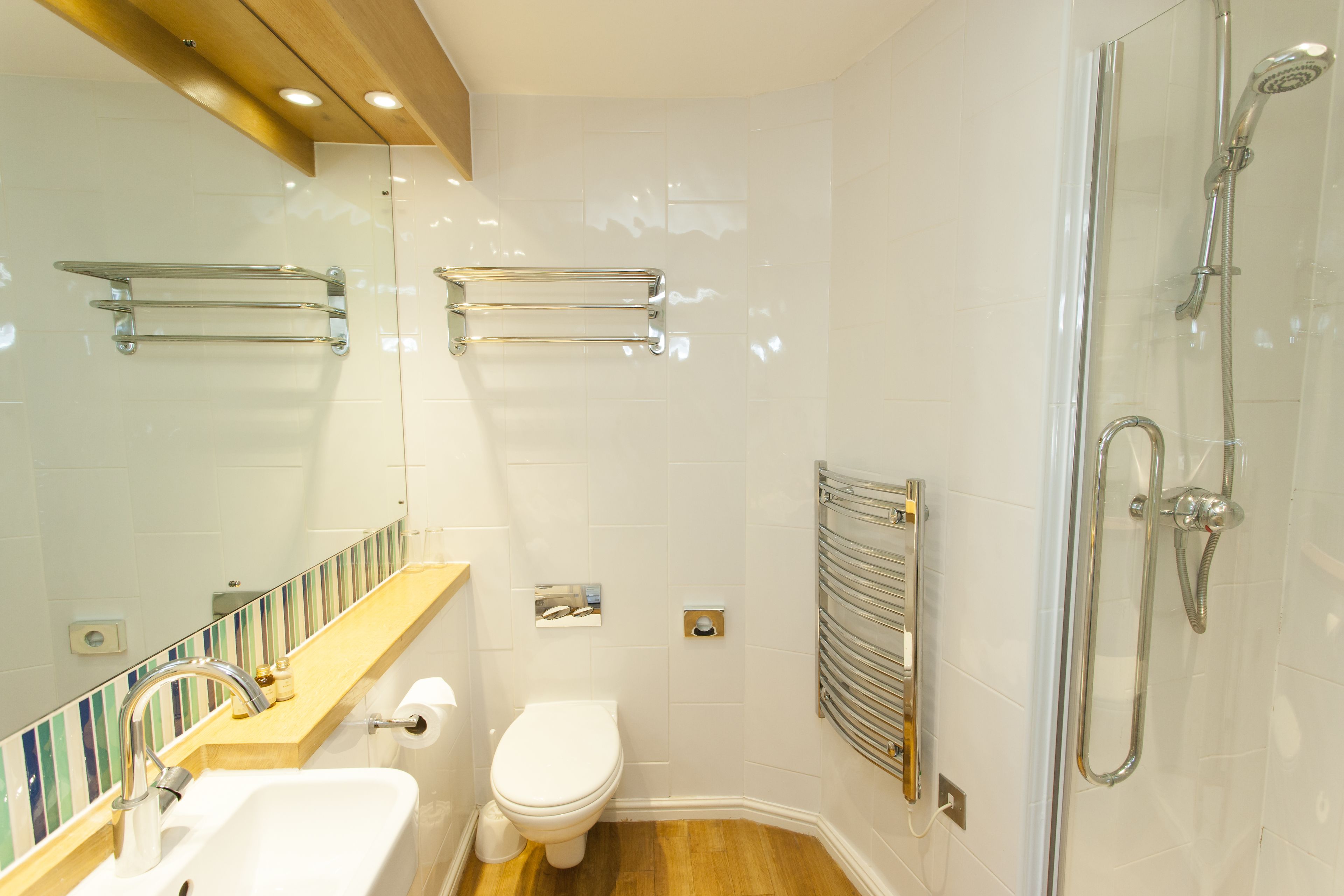 A bathroom with a sink, toilet, mirror, shower, and towel rack.