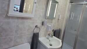 Une salle de bain équipée de toilettes, d’un lavabo, d’un miroir et d’une douche.