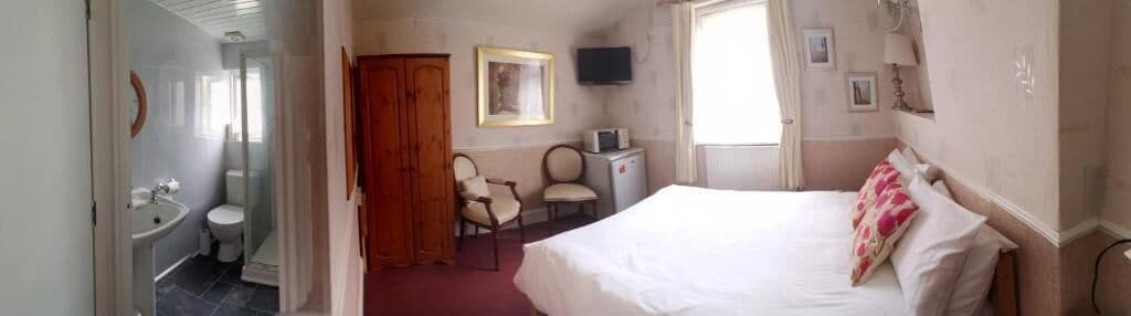 A hotel room with a bed, a desk, a chair, a television, and a bathroom.