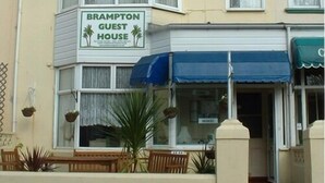 A guest house named Brampton Guest House with a signboard, outdoor seating, and a blue awning. - Brampton Guest House (Paignton)