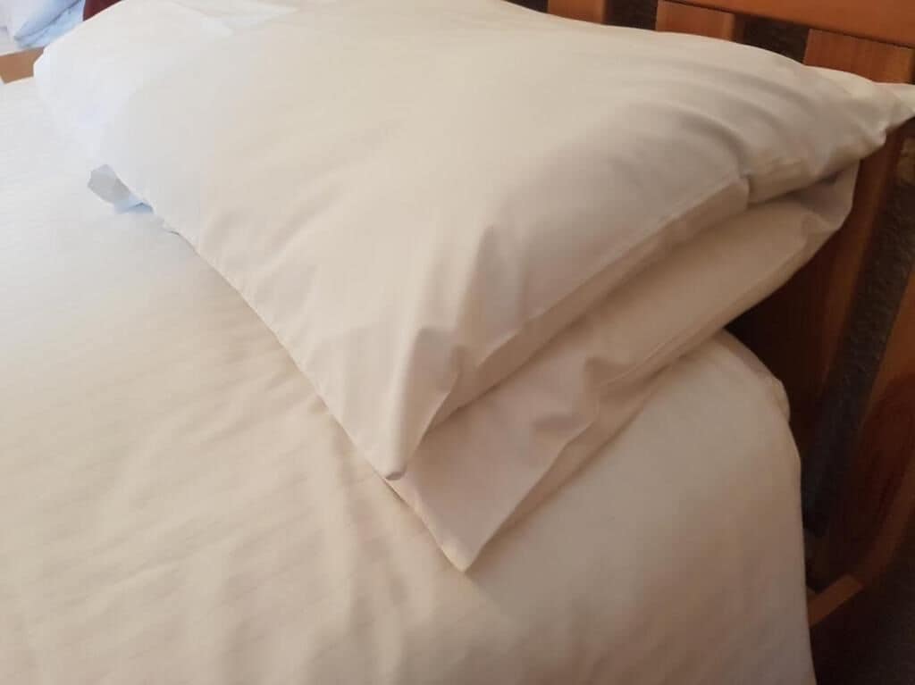 Un lit avec une literie blanche et une tête de lit en bois.