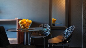 A modern room with a round table, two chairs, and a bowl of fruit on the table.