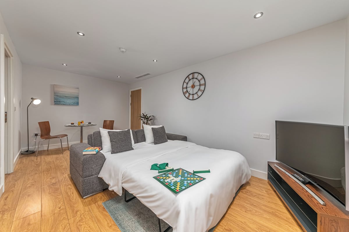 Une chambre d’hôtel moderne avec un grand lit, un téléviseur à écran plat, une petite table avec des chaises et un tableau au mur.