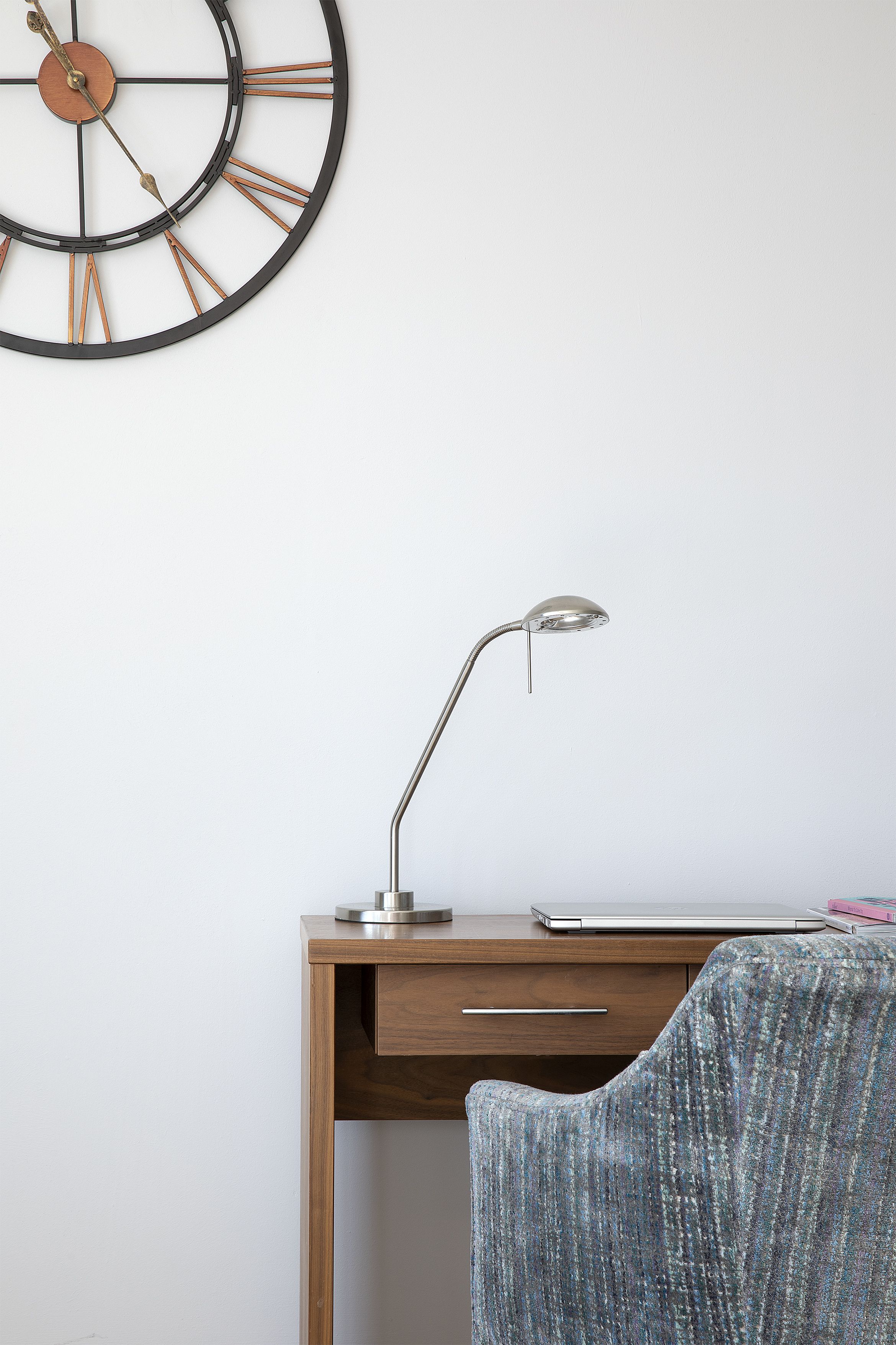 A desk with a laptop, a desk lamp, and a chair.