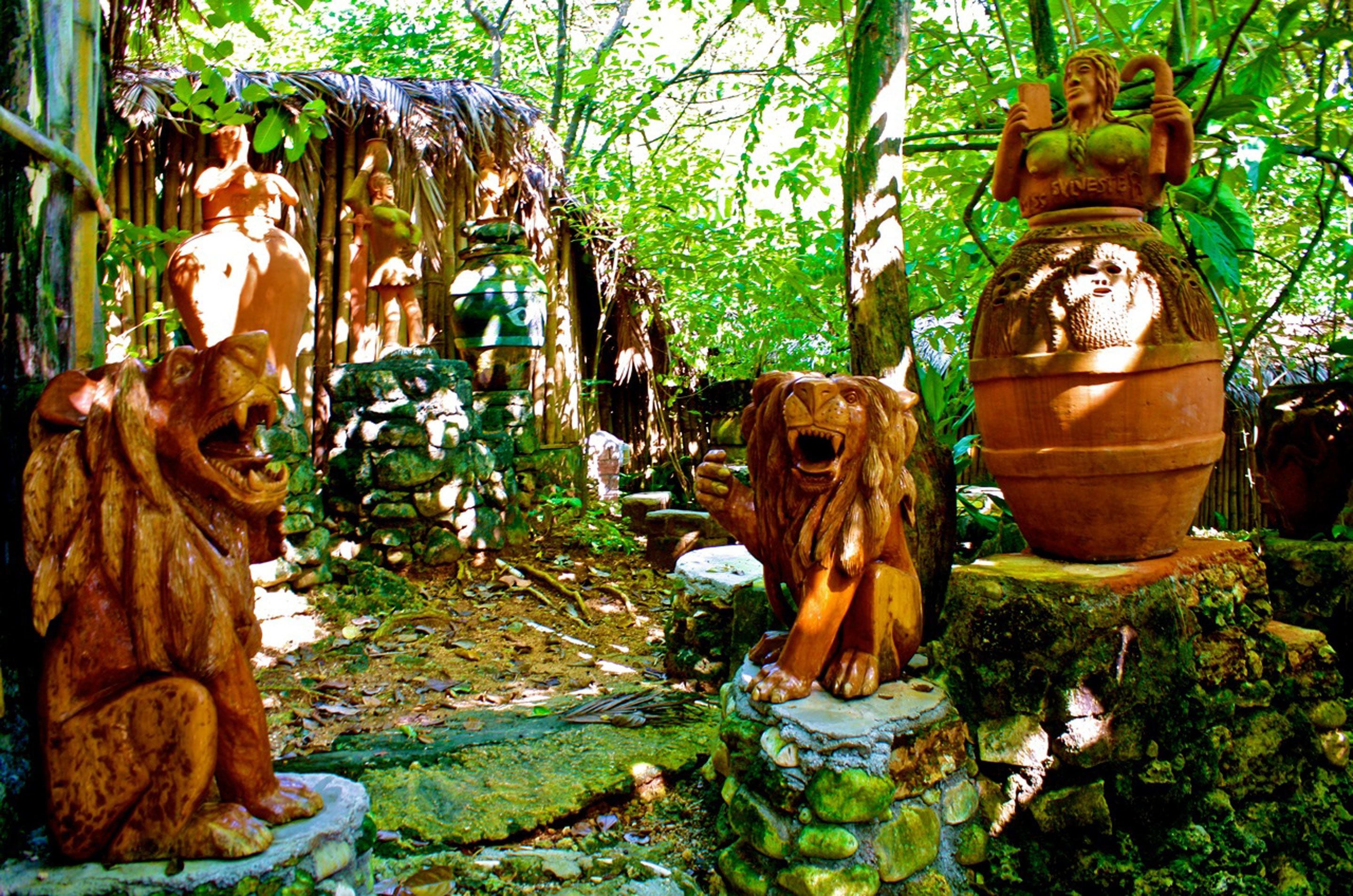 Un jardín rústico con estatuas de perros y una maceta de barro grande.