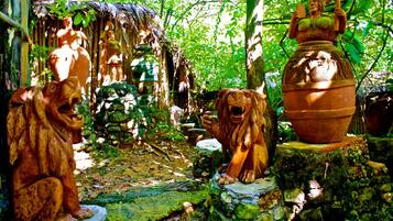 Un giardino rustico con statue di pietra raffiguranti cani e un'ampia vasca in terracotta.