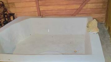Una bañera con techo de madera y desagüe visible.