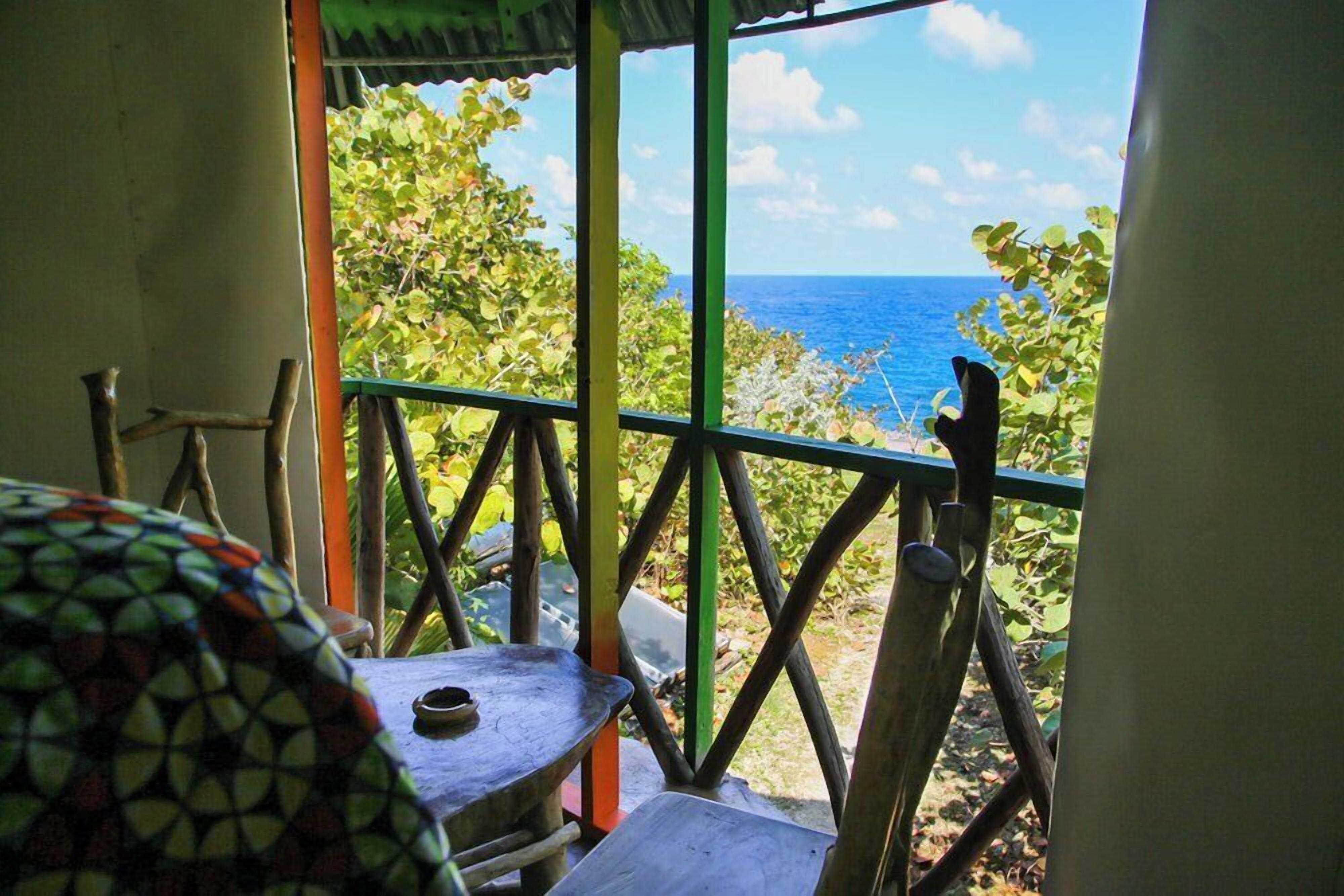 A room with a view of the ocean, a table, and a chair.