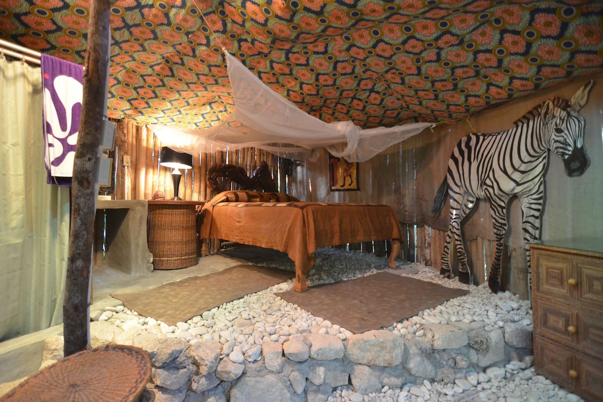 A room with a bed, a zebra decoration, and a patterned ceiling.
