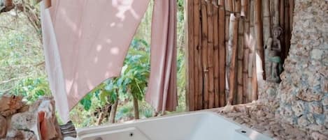 A spa area with a hot tub, bamboo walls, and a stone wall.