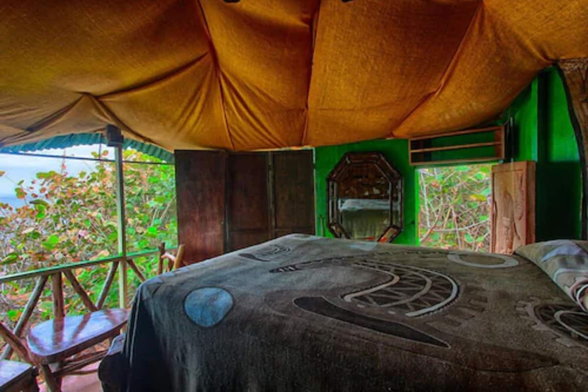 A room with a bed, a chair, and a view of the outdoors.